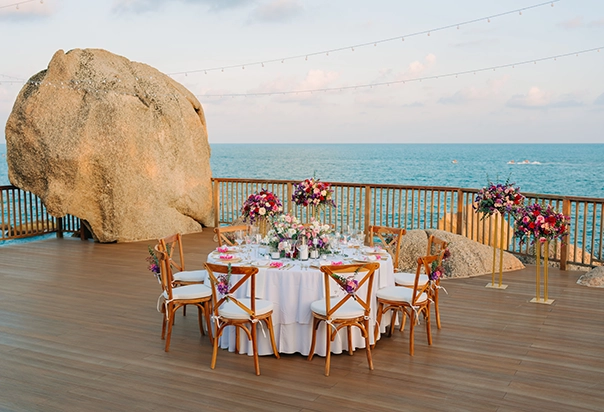 Runder Tisch für ein intimes Hochzeitsdinner auf dem Sundeck des Silavadee Pool Spa Resort mit tropischer Blumendekoration und Meerblick