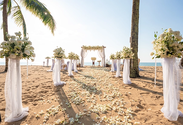 Weiße Hochzeitsdekoration für eine Strandhochzeit in Khao Lak mit Blumenständern und Bambuspavillon mit weißer Stoffdekoration